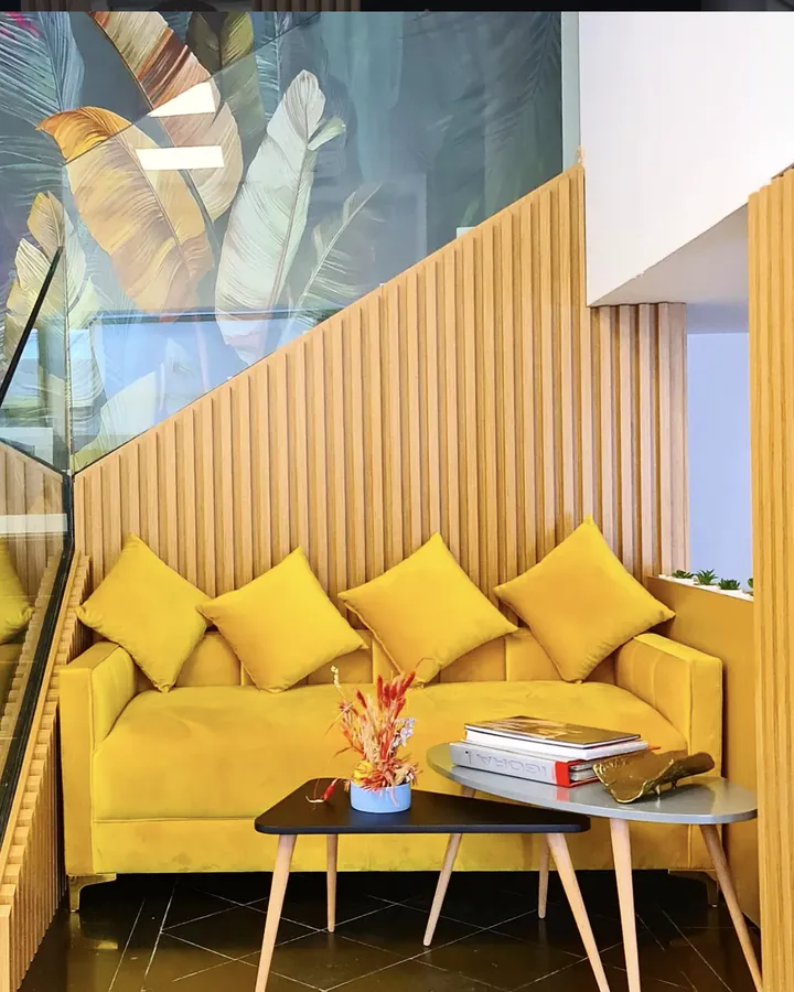 Coin d'attente du salon, canapé jaune et fresque tropicale